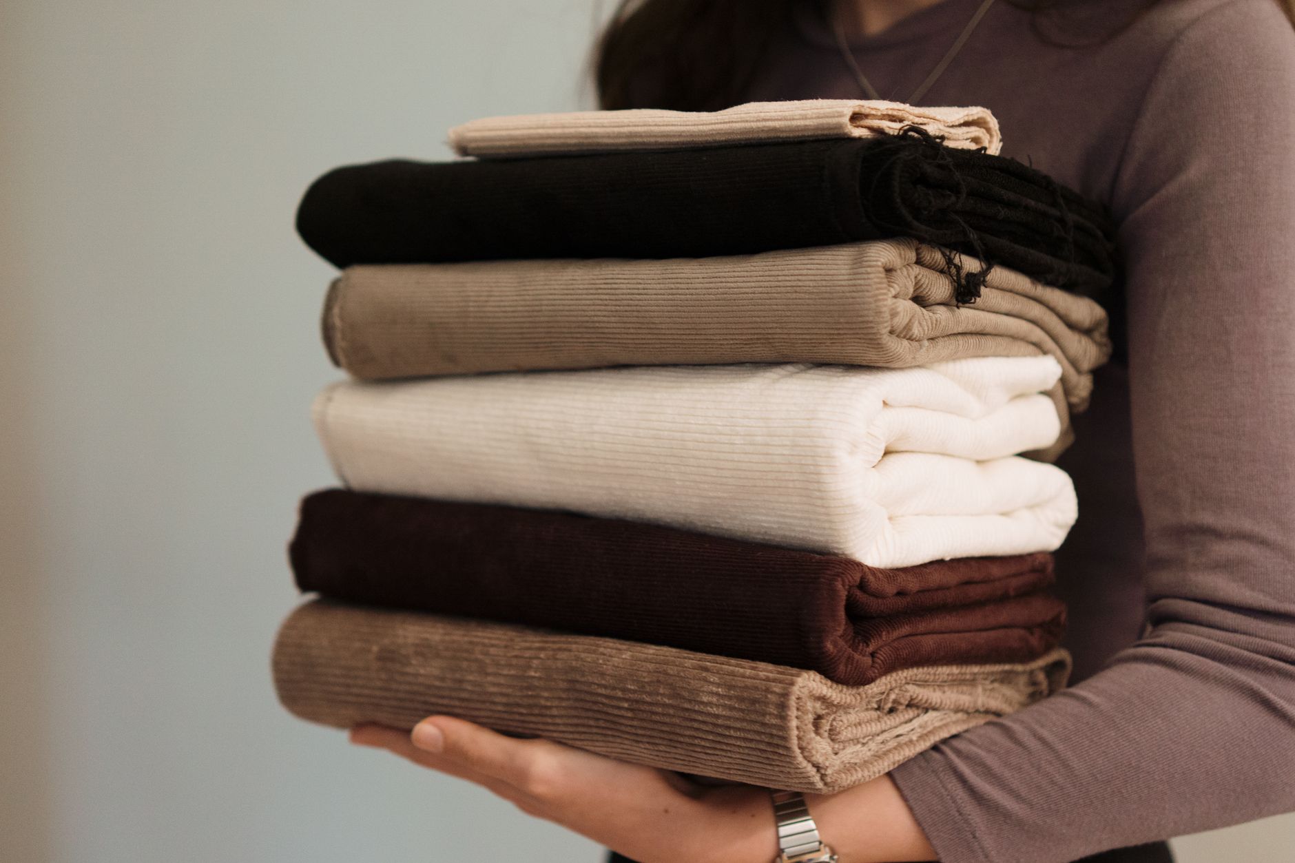 Folded neutral autumn clothes on a bed