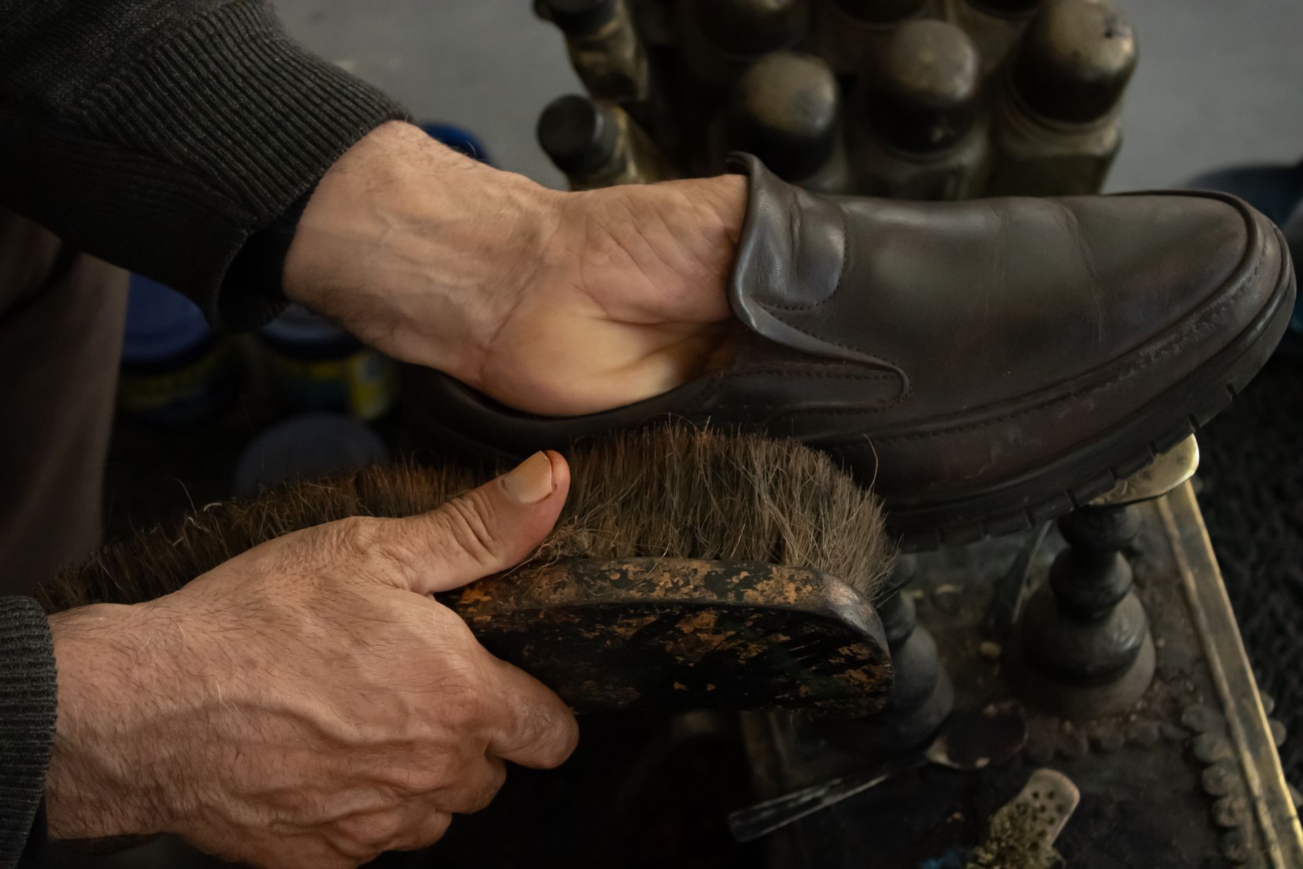 A shoe polish tin and brush next to leather shoes