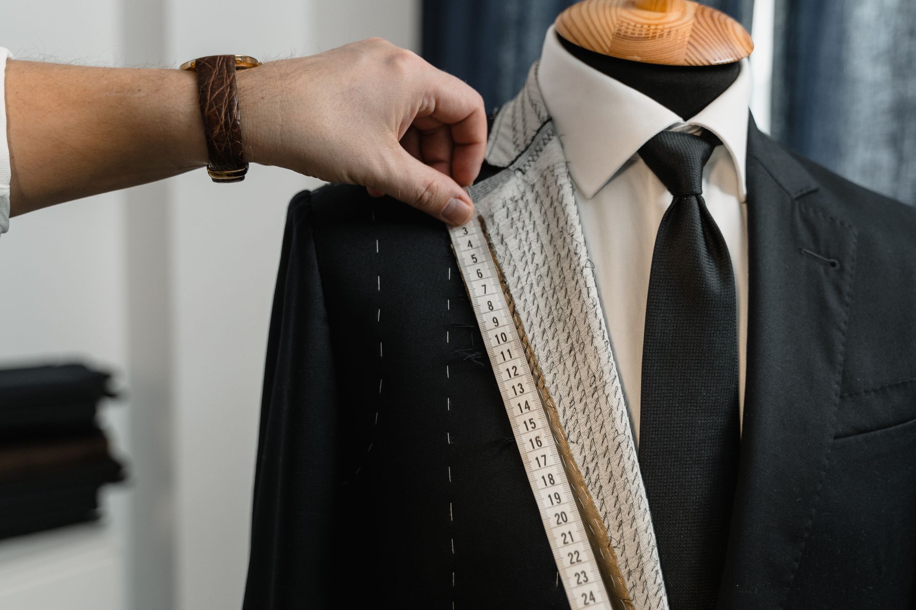 A tailor measuring a jacket with a tape measure