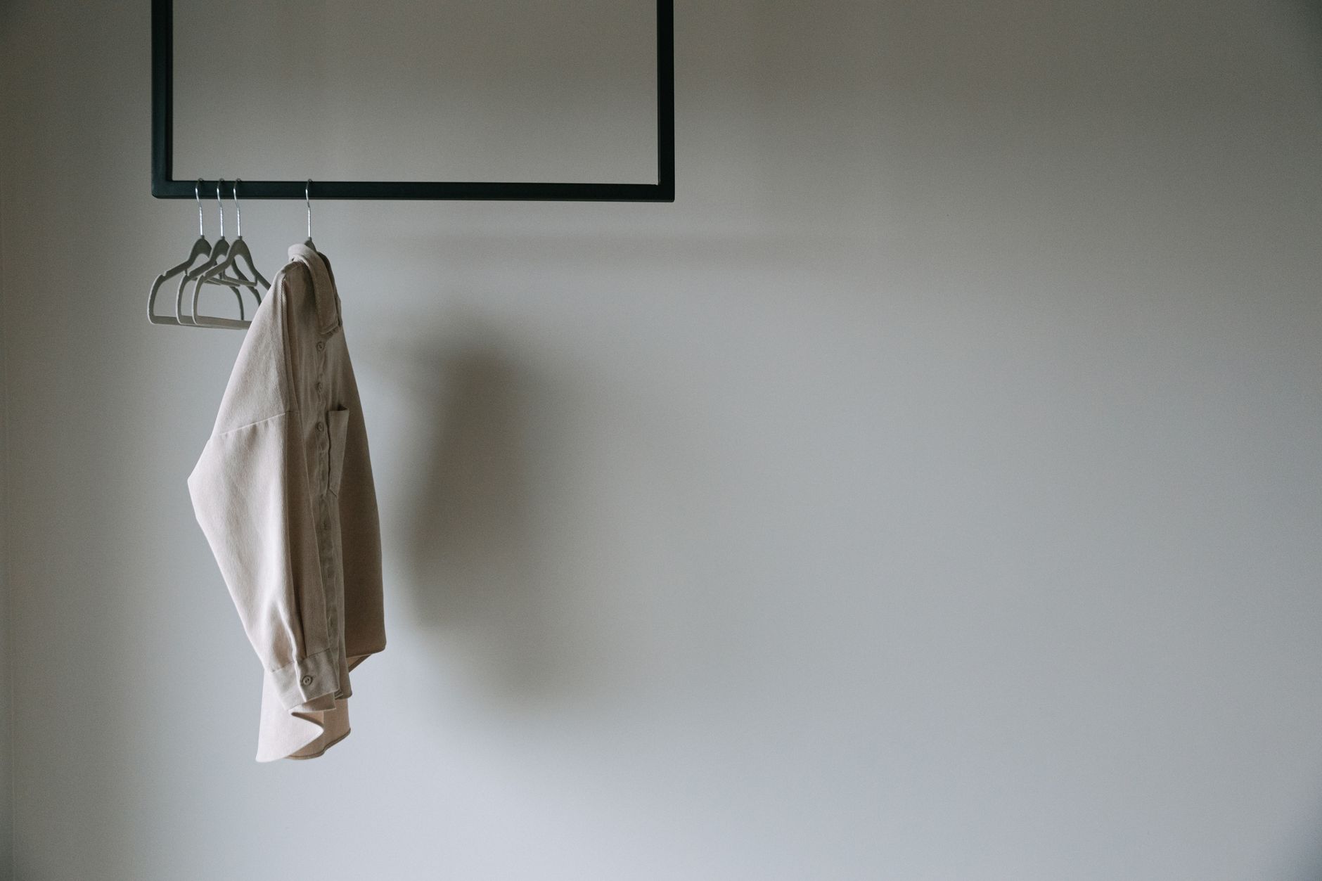 A neutral minimalist coat on a hanger