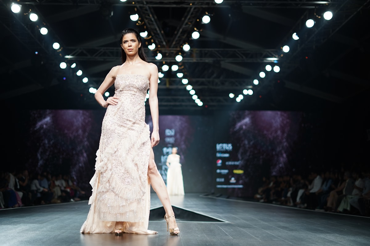 Model in an elegant white sheer dress on a fashion runway